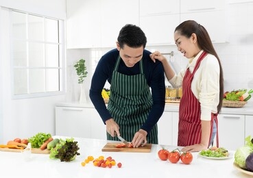 perfect marriage couple cooking and preparing ingredient in kitchen at home. wife looking at husband cutting vegetables for salad. white background - copy space.