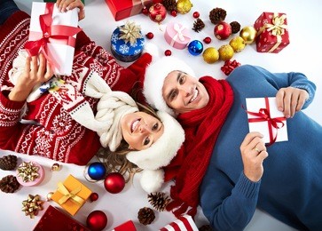 happy couple with christmas gifts relaxing at home