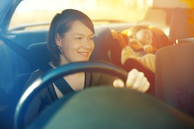 the child in a safety seat near to mother who sits on forward sitting of the car.