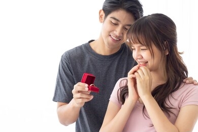 happy lover, man surprises his pretty girlfriend with wedding ring , will you marry me. a diamond gold ring in red box. valentine's day celebration, asian couple isolated on white background.  