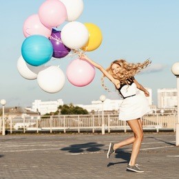 happy young woman having fun with colorful latex balloons.  gorgeous thick wavy hair. outdoors, lifestyle