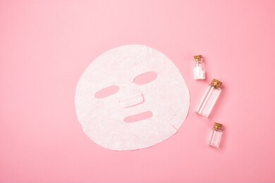 facial sheet mask for beauty facial massage therapy. cosmetic bottle with liquid serum and roller for face massage