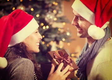 christmas gift. happy couple in santa's hat with christmas and new year gift at home. smiling family together. christmas tree 