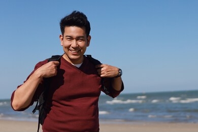 happy traveler asian man in red shirt by the sea.