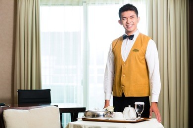 asian chinese room service waiter or steward serving guests food in a grand or luxury hotel room 