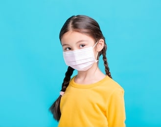sick girl child in medical mask isolated on blue background