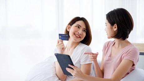 two asian women use tablet for online shopping purpose and pay with credit card.