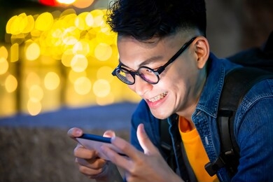 asian young man watch video on phone outdoor in the evening