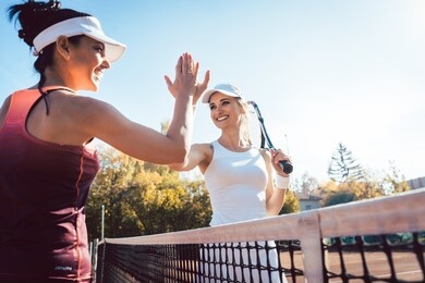 women giving high five after a good and friendly match of tennis