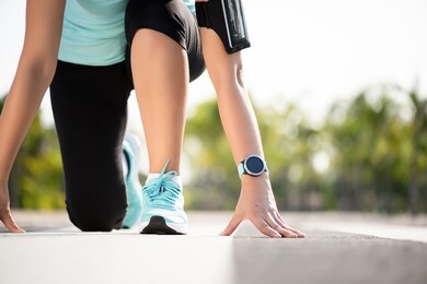 front view of athletic women in running start pose on running track in the garden street. sport and running concept.