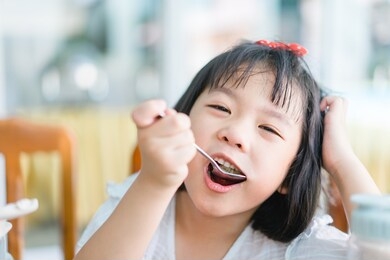 hungry face and enjoy eating concept.little asian girl enjoy eating with rice and vegetable on a plate in lunch time at home.asian kid girl holding spoon with white rice and open her mouth.