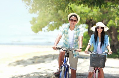 carefree couple having fun and smiling riding bicycle at the beach