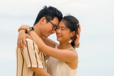 sweet and romantic lifestyle portrait of young happy asian korean couple in love enjoying holiday on beautiful beach walking together by the sea playful and affectionate in relationship concept