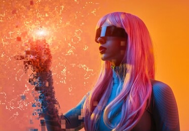 young futuristic lady in vr glasses and pink wig touching pixels in virtual reality against orange background