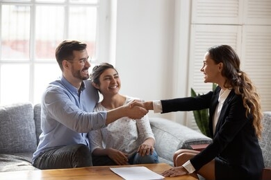 female realtor or landlord shake hands with multiracial couple real-estate buyers make deal sign rental agreement or sale purchase contract, agent and happy clients renters, buying first home concept