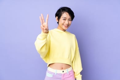 young vietnamese woman with short hair over isolated purple background happy and counting three with fingers