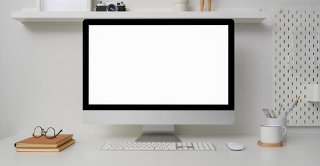 close up view of minimal workspace with blank screen computer, office supplies and decorations on white desk with shelf on white wall 