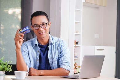 attractive asian businessman showing credit card debit card to purchase and happy shopping concept. consumer experience