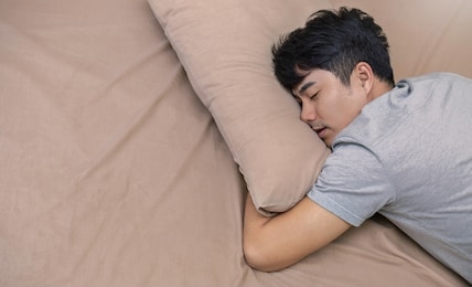 portrait of young happy asian man with attractive smile sleeping laying indoor apartment bed room . asian man sleep tight in bed with copy space. healthy care good night sleep concept