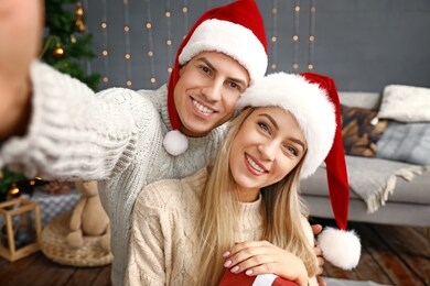 happy couple with christmas gift taking selfie at home