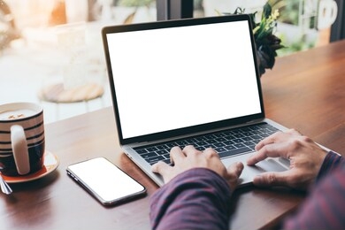 computer,cell phone mockup image blank screen with white background for advertising text,hand man using laptop texting mobile contact business search information on desk in cafe.marketing,design