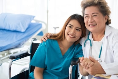 happy asian patient on wheelchair and doctor in hospital room. smiling asian sick woman recovered & get moral support from physician. patient got health insurance. smiling doctor and patient concept. 