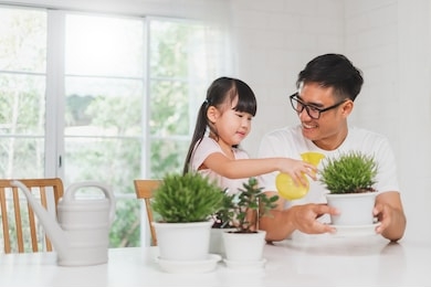 asian cute girl help father to plant flowers, watering at home, asian family home gardening concept