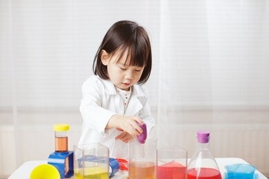 toddler girl pretend play  scientist  role  at home against white background
