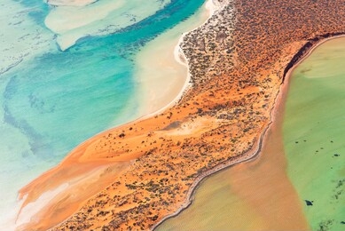 rusty colored dunes surrounded by beautifully colored water.  shark bay world heritage area in western australia.