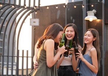group of asian friend cheering and drinking at terrace party. young people enjoying and hanging out on rooftop at sunset. friendship ,youth lifestyle and nightlife concept.