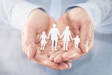 hands with cut out paper silhouette on table. family care concept.