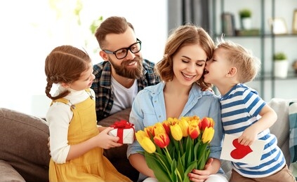 happy mother's day! father and children congratulate mother on holiday and give flowers
