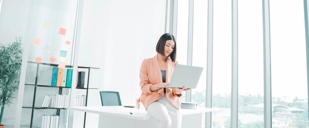 attractive young asian businesswoman working on a laptop at table in workstation office, thai girl enjoy browsing for online shopping store with copy space for advertisement, for banner websites 