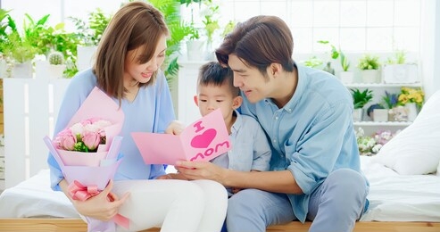 family celebrate happy mother day - child and mom read card at home