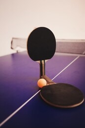 two table tennis or ping pong rackets and balls on a blue table