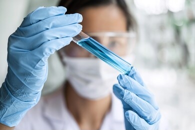 scientist or medical in lab coat holding test tube with reagent, laboratory glassware containing chemical liquid, microscope, biochemistry laboratory research.