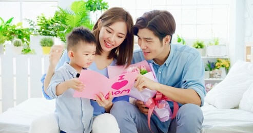 family celebrate happy mother day - child and mom read card at home