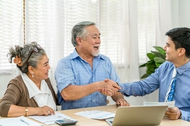 insurance agency manager handshake with asian couple grandparent in happy feeling after deal the agreement successful,financial planner presenting and closing the sale of real estate,document and bill