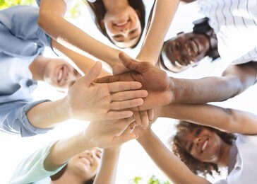 student friendship. portrait of happy university friends stacking hands together, showing unity and togetherness, low angle view, selective focus