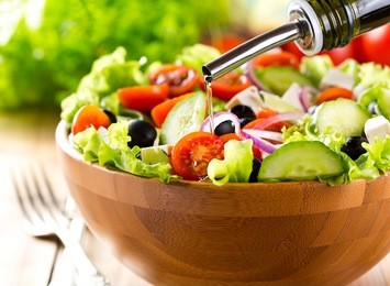 oil pouring into bowl of salad
