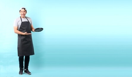 dining concept. asian man waiter holding an empty plate.isolated on blue background in studio with copy space.