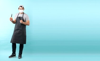 full body portrait of cheerful positive barber with  having scissors in hand and comb,isolated on blue background in studio with copy space.