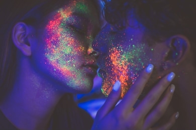 couple kissing in the disco club with fluorescent paintings on the faces