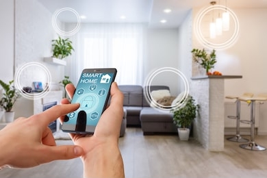 smart home technology interface on smartphone app screen with augmented reality (ar) view of internet of things (iot) connected objects in the apartment interior, person holding device