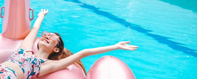 happy traveler asian woman with bikini relax on big pink flamingo pool float in swimming pool at day, summer travel vacation concept