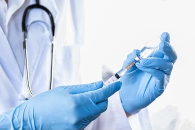 doctor, nurse or scientist hand in blue nitrile gloves holding flu, measles, coronavirus vaccine shot for diseases outbreak vaccination, medicine and drug concept