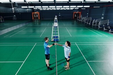young male and female badminton players shaking hands after training in gymnasium