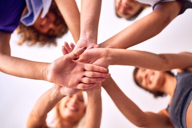 young beautiful group of sportswomen standing shaking hands after class of yoga at gym