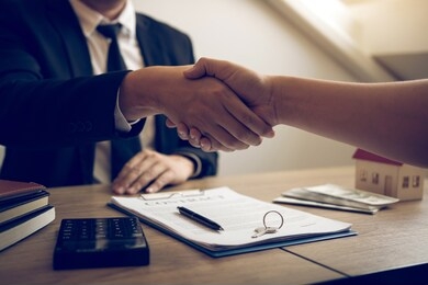 home sales agents and buyers work on signing new homes and shaking hands.