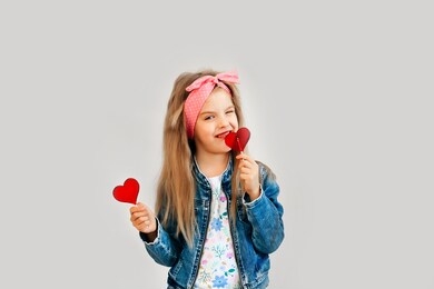 portrait of a beautiful stylish fashionable girl in glasses, with a heart-shaped lollipop, on a white background, free time summer vacation. close up, selective focus